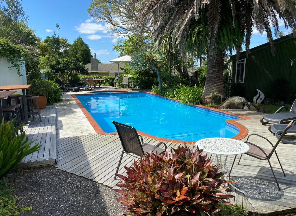 a swimming pool with a table and chairs next to it at Colonial House Motel in Kerikeri