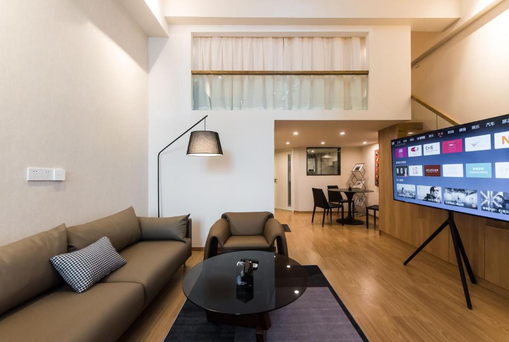 a living room with a couch and a flat screen tv at WESU Apartment Shenzhen Futian Bagualing Branch in Shenzhen