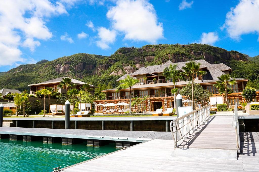 a resort on the water with a mountain in the background at L'Escale Resort Marina & Spa - Small Luxury Hotels of the World in Mahe