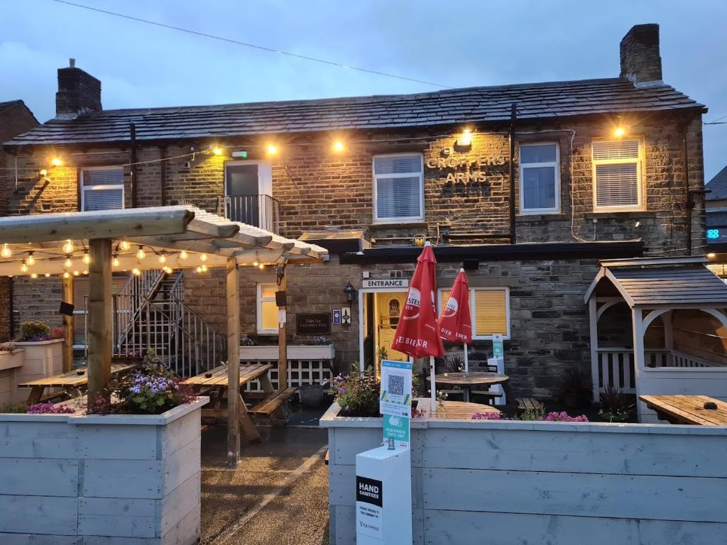 un bâtiment avec des tables et des parasols devant lui dans l'établissement Croppers Arms, à Huddersfield