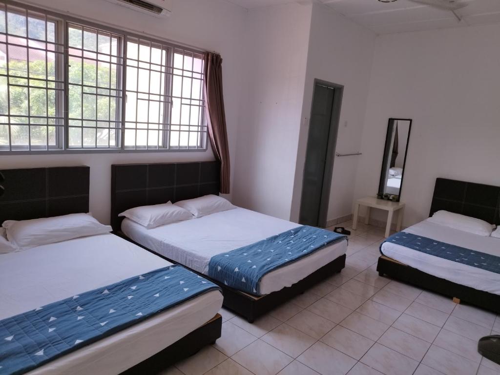 um quarto com 2 camas e 2 janelas em Wong Bentong Makmur Homestay em Bentong