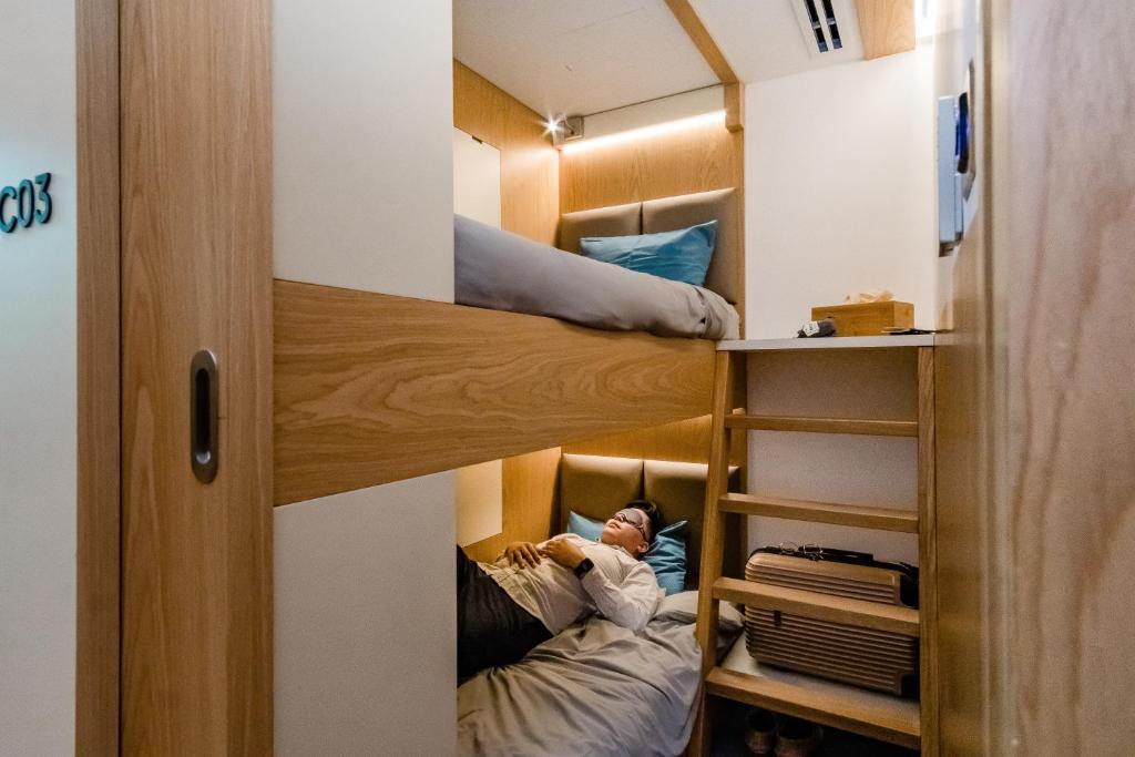 una camera con due letti a castello e un uomo steso in loro di sleep 'n fly Sleep Lounge & Showers, B-Gates Terminal 3 - TRANSIT ONLY a Dubai