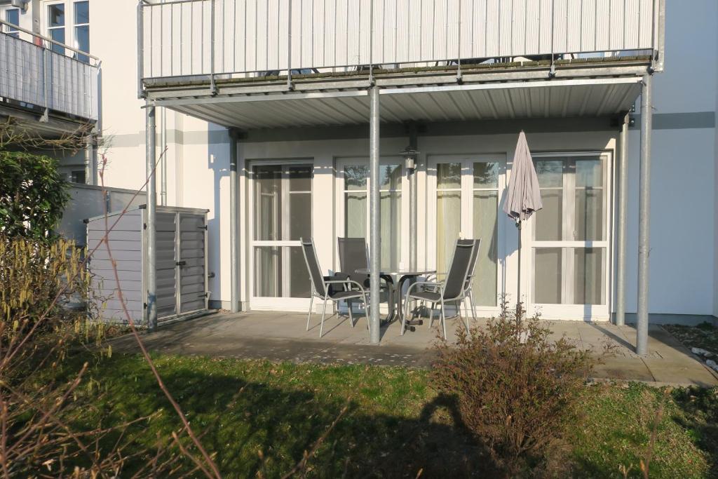 ein Haus mit einer Terrasse mit Stühlen und einem Sonnenschirm in der Unterkunft Erdgeschosswohnung Gerbera im Haus Isabella in Zinnowitz