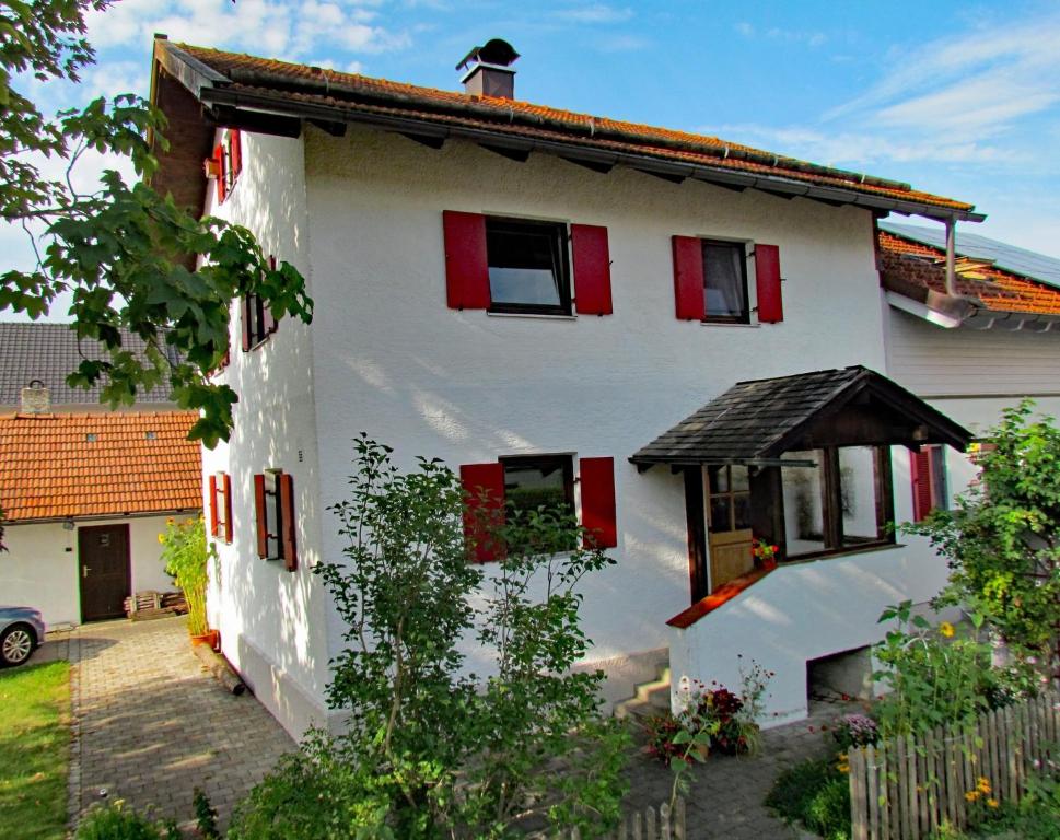 een wit huis met rode luiken erop bij Haus Erle in Peiting
