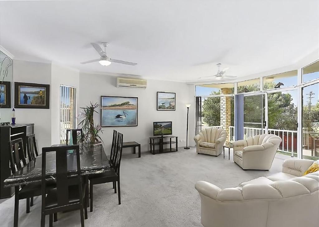 a living room with a table and a dining room at Solitaire 1 in Sawtell