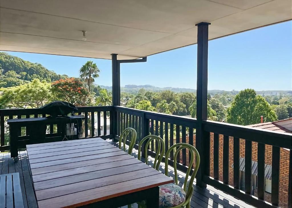 een houten terras met een tafel en stoelen op een balkon bij On the Hillside in Coffs Harbour