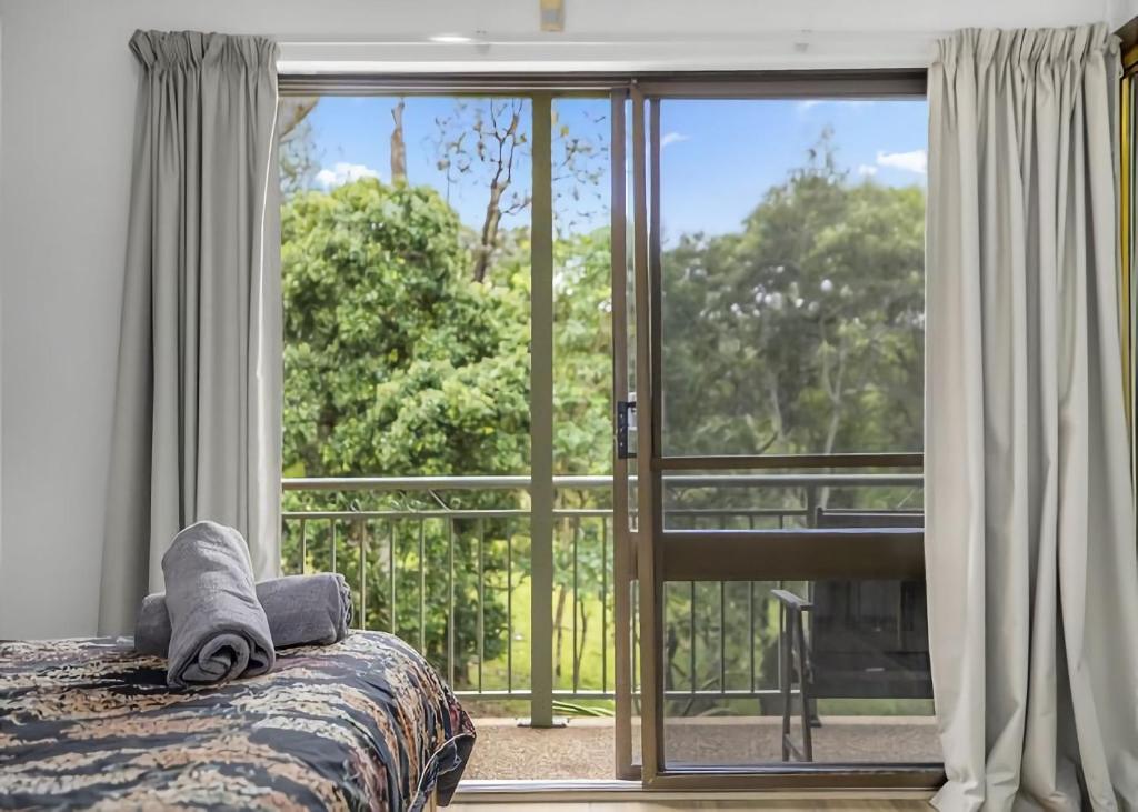 a bedroom with a bed and a large window at Banksia in Sawtell