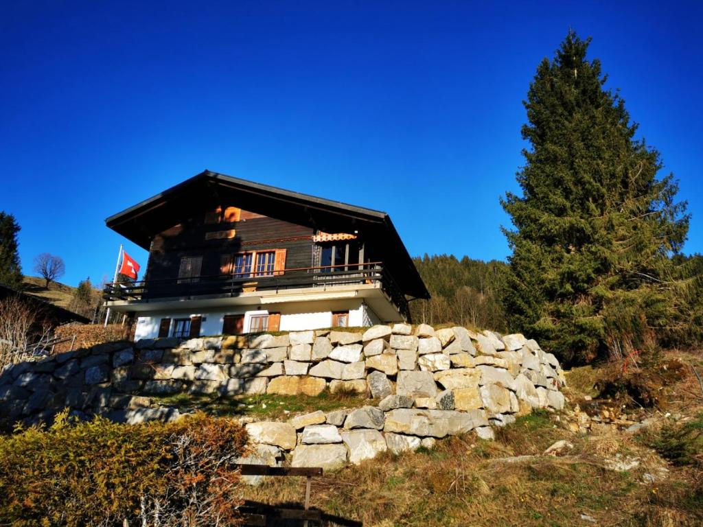 a house on a hill with a stone wall at Ferienwohnung im Chalet am Bach in Schwarzsee