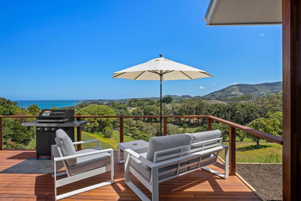 een terras met twee stoelen en een parasol en een grill bij Ciao Korora in Coffs Harbour