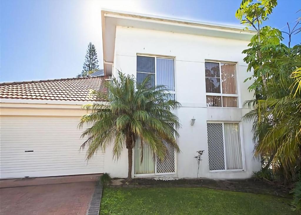una casa bianca con una palma di fronte di 1/17 22nd Ave - Sawtell, NSW a Sawtell