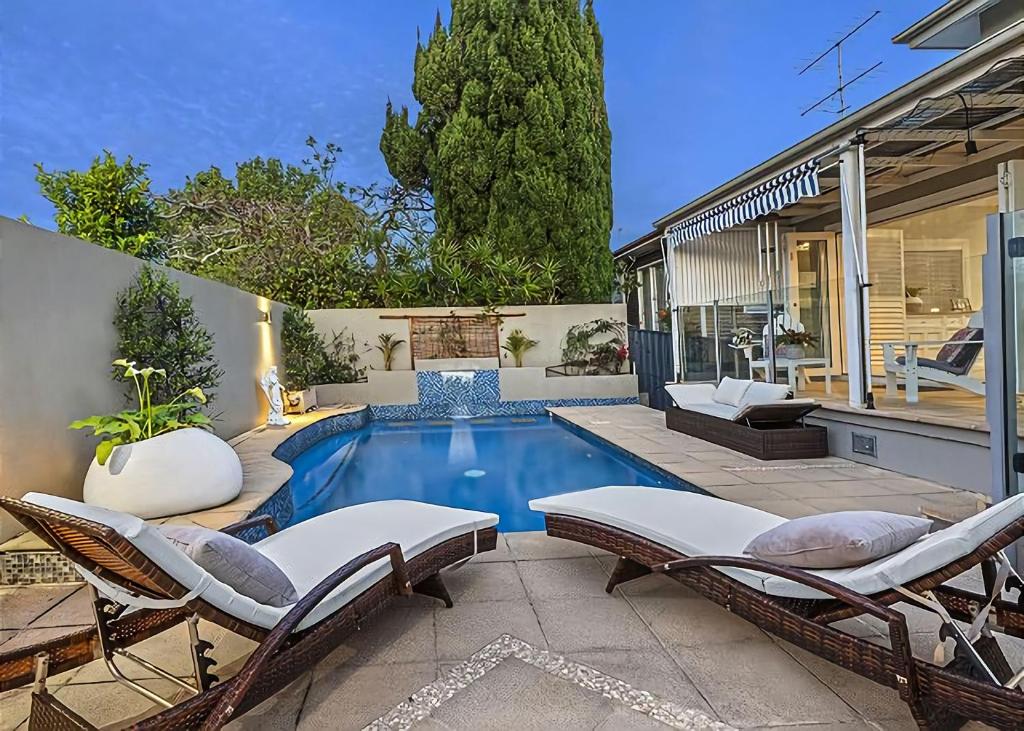 a swimming pool with chairs and a house at Sea Breeze in Coffs Harbour