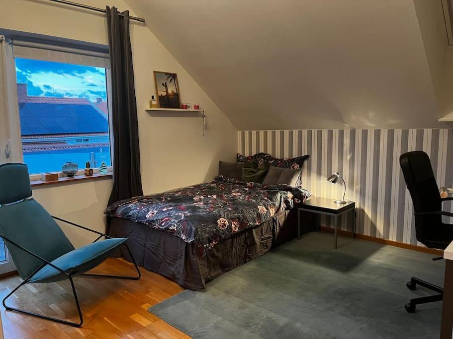 a bedroom with a bed and a chair and a window at Modern stor villa nära havet och 10 min till city in Gothenburg