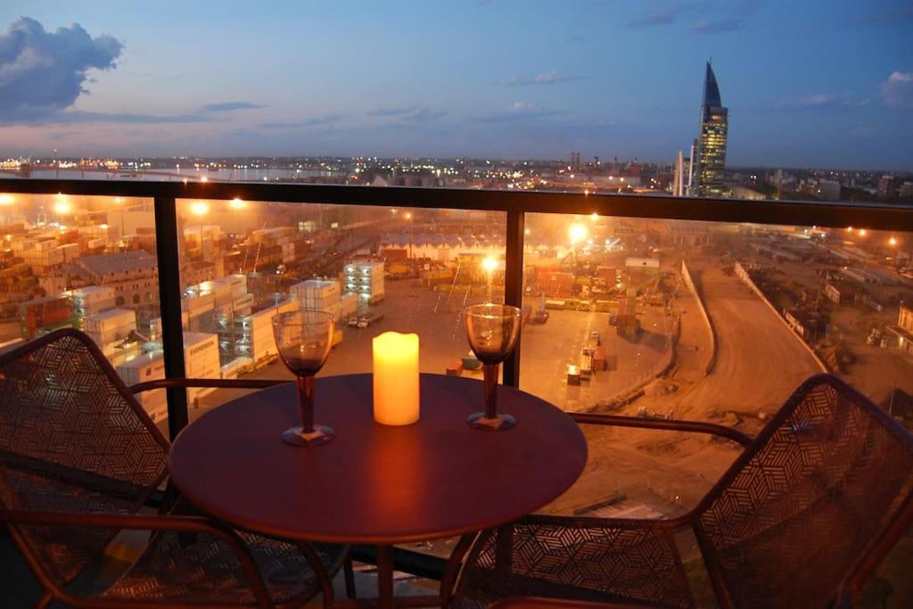 a table with two wine glasses and a candle on a balcony at Apartamento nuevo, centrico y con vista a la bahia in Montevideo