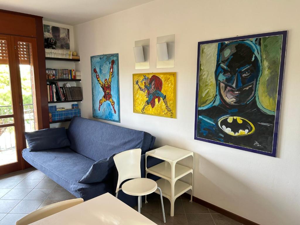 a living room with a blue couch and a batman painting at Appartamento in centro con terrazze e parcheggio gratuito in Lignano Sabbiadoro