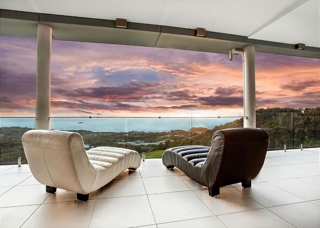 two chairs and a couch in front of a large window at Belvedere in Kororo Basin