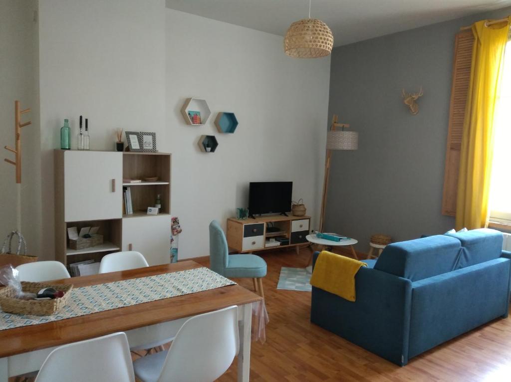 ein Wohnzimmer mit einem blauen Sofa und einem Tisch in der Unterkunft Appartement calme proche de la Loire in Saumur