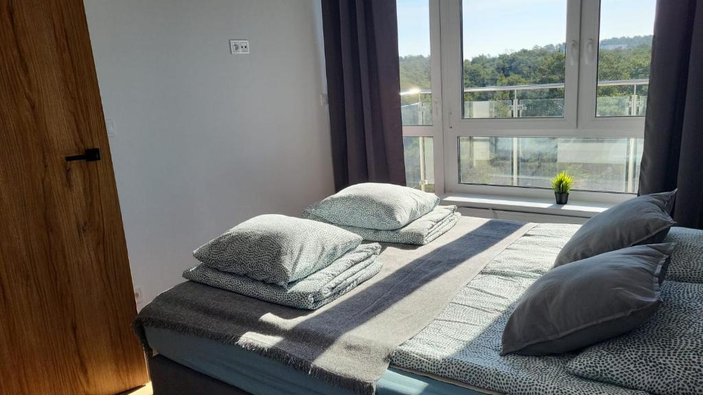1 cama con almohadas en una habitación con ventana en Apartamenty Piaskowe, en Rowy