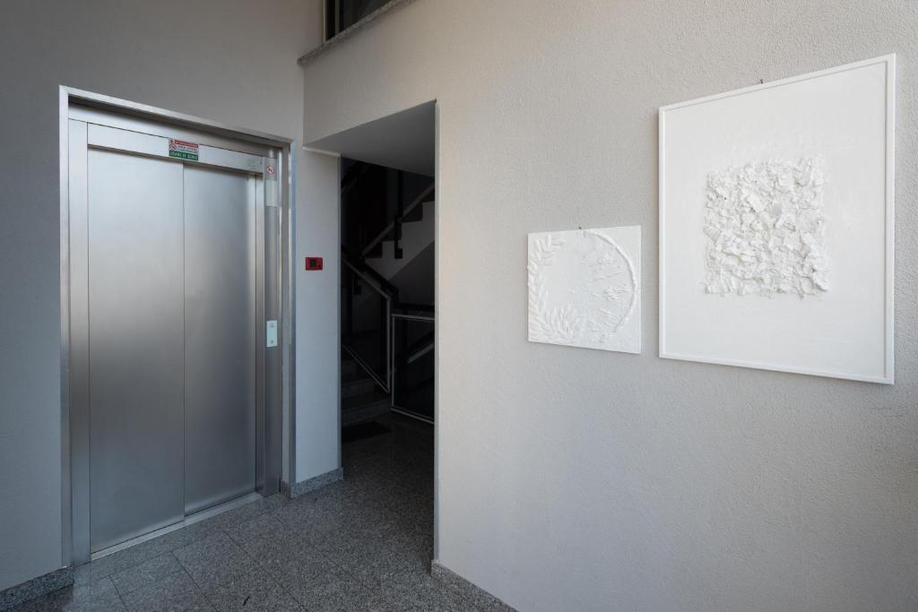 a hallway with two paintings on a wall and a door at Bed&Business Nick Bellezza-San Siro Stadio-Rho Fiera in Settimo Milanese