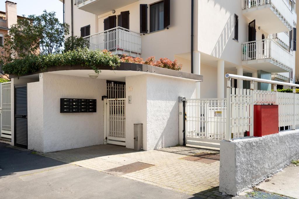a white building with a gate and a red door at Bed&Business Nick Bellezza-San Siro Stadio-Rho Fiera in Settimo Milanese