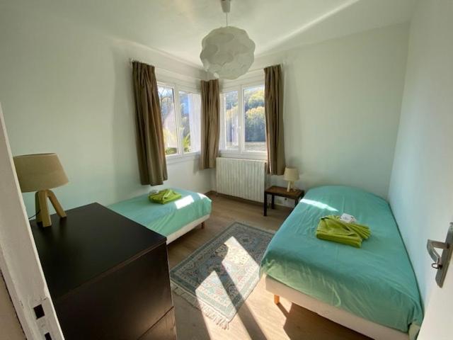 een slaapkamer met 2 bedden, een bureau en een raam bij Un Havre de paix en bordure de la Dordogne in Lalinde
