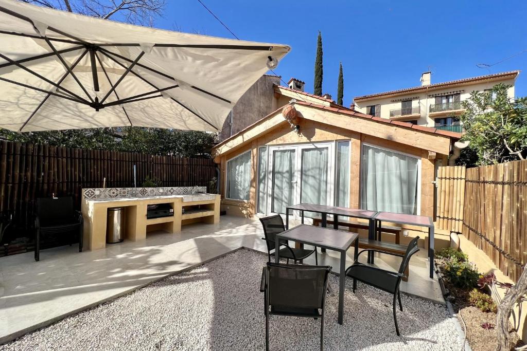 une terrasse avec une table, des chaises et un parasol dans l'établissement Leon's house in Saint Aygulf, à Fréjus