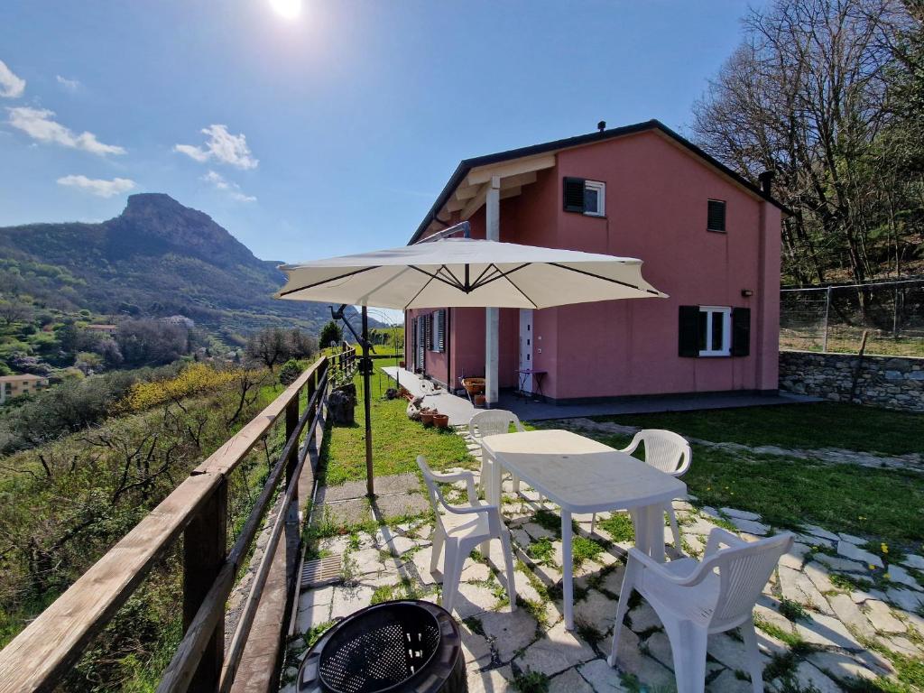 une terrasse avec une table, des chaises et un parasol dans l'établissement Nel verde Ligure , “non solo mare” outdoor e relax, à Calice Ligure