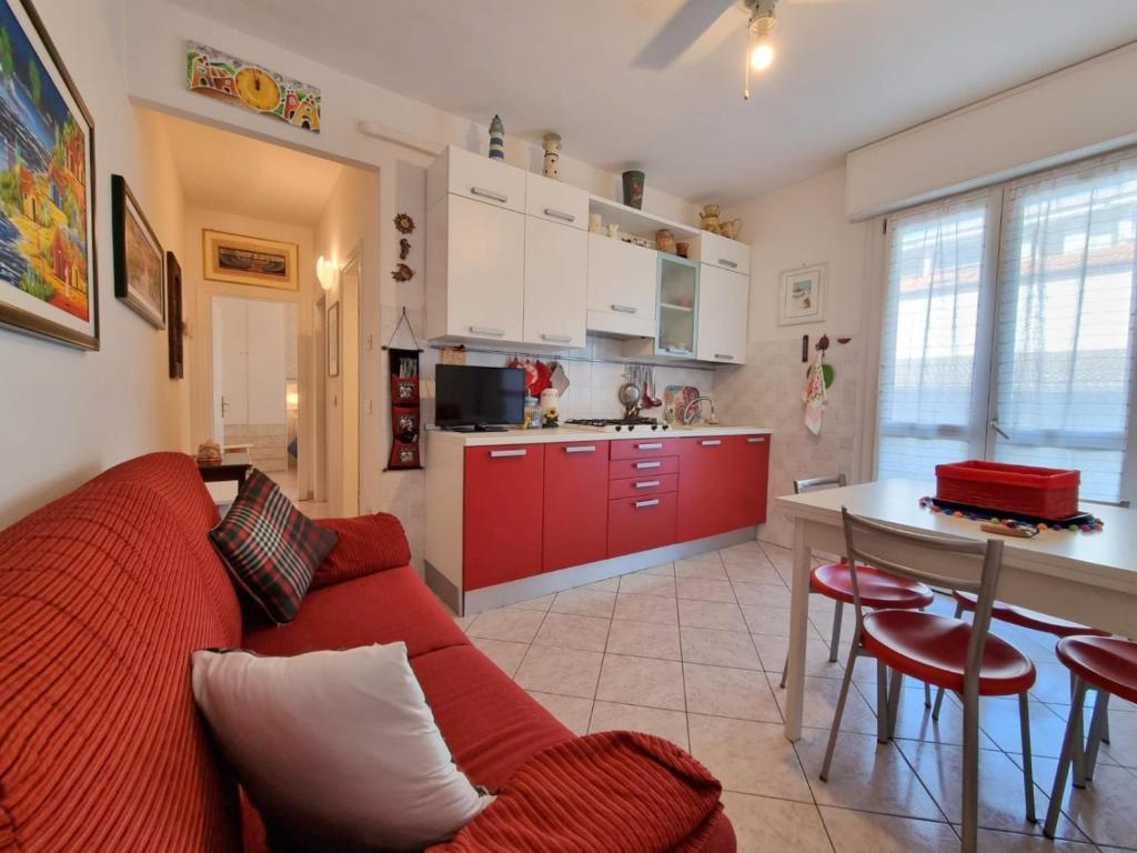 a living room with a red couch and a kitchen at Aurora 2 in Lido di Pomposa