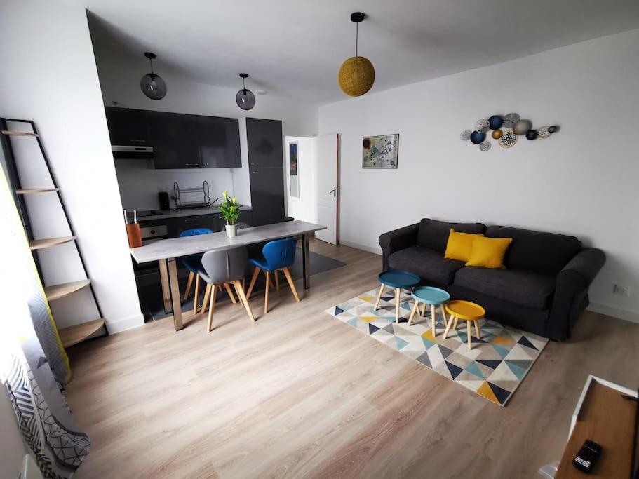 een woonkamer met een bank en een tafel en stoelen bij Le Puzzle in Trélazé