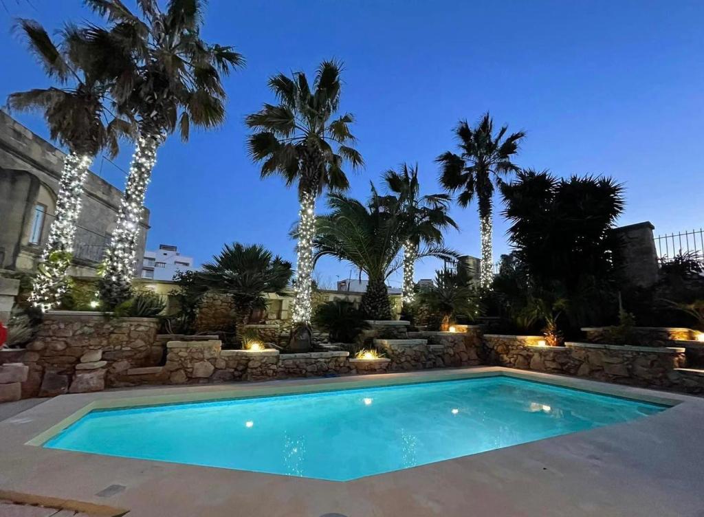 a swimming pool in a yard with palm trees at Ta' Tereza in Xagħra