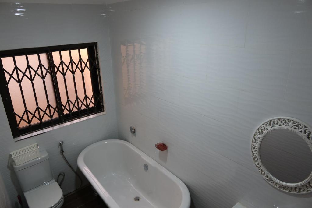 a white bathroom with a sink and a mirror at Katonga Lolani Apartment in Lusaka