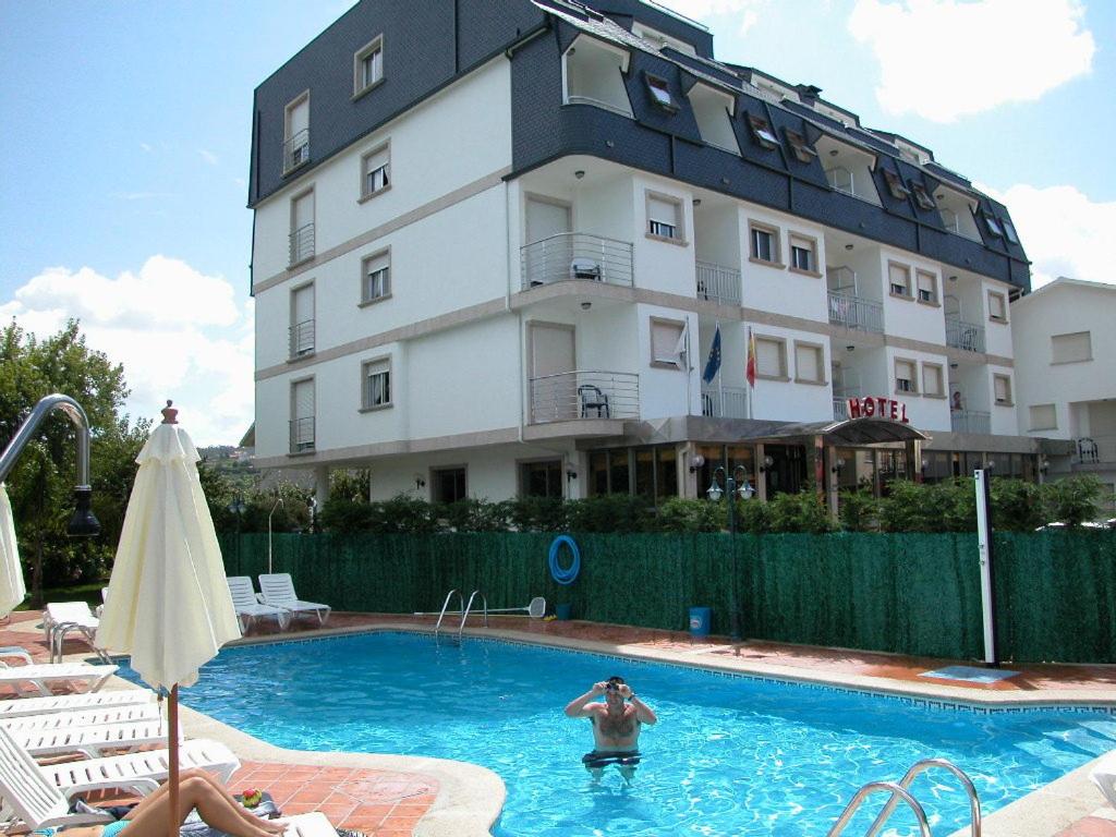 a man in a swimming pool in front of a building at Hotel Piñeiro 2 Estrellas Superior in A Lanzada