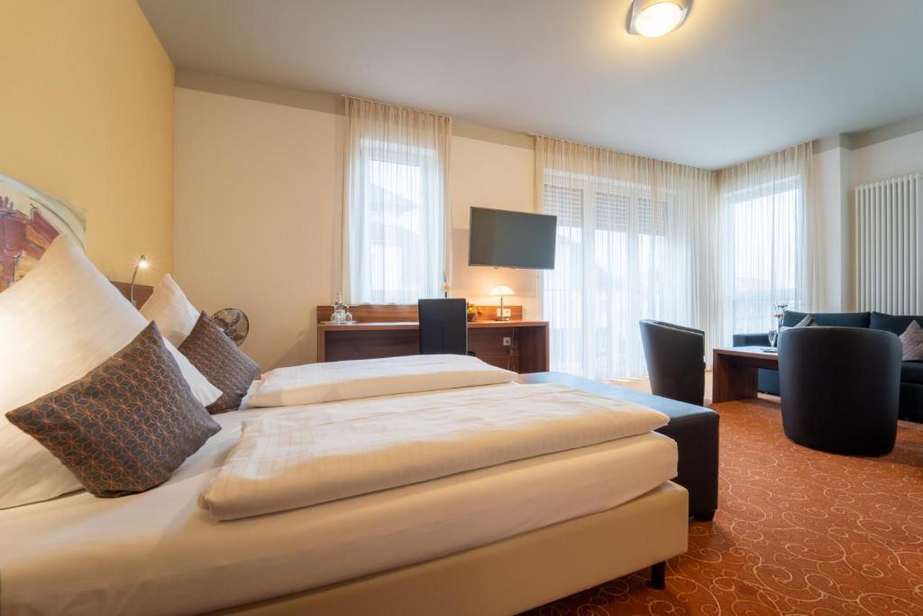 Cette chambre comprend deux lits et un bureau. dans l'établissement Hotel St Georg - Regensburg, à Ratisbonne