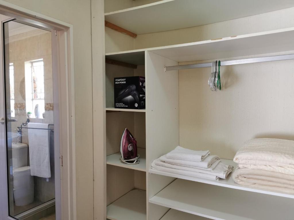 a bathroom with a closet with towels on shelves at Exclusive Private Room in Joburg No loadshedding in Johannesburg