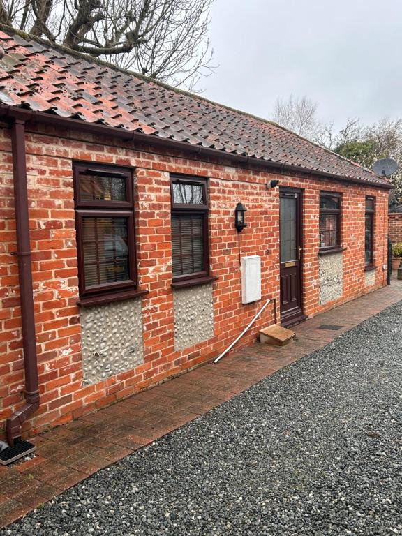 un edificio de ladrillo con ventanas laterales en The Old Stables in Mews en Kessingland