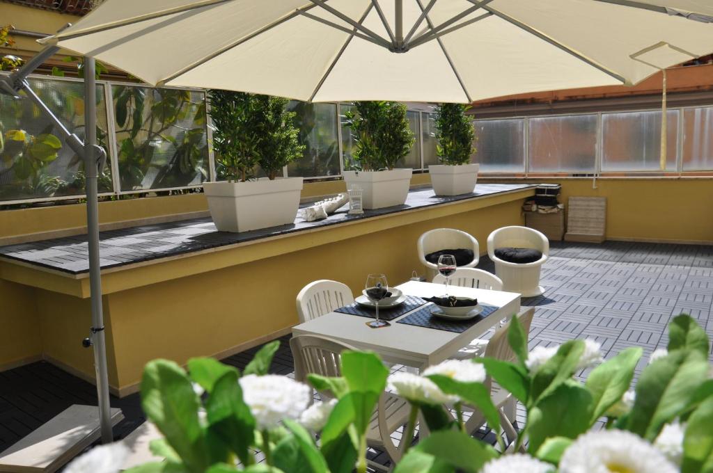 patio ze stołem, krzesłami i parasolem w obiekcie Maison Romana w Rzymie