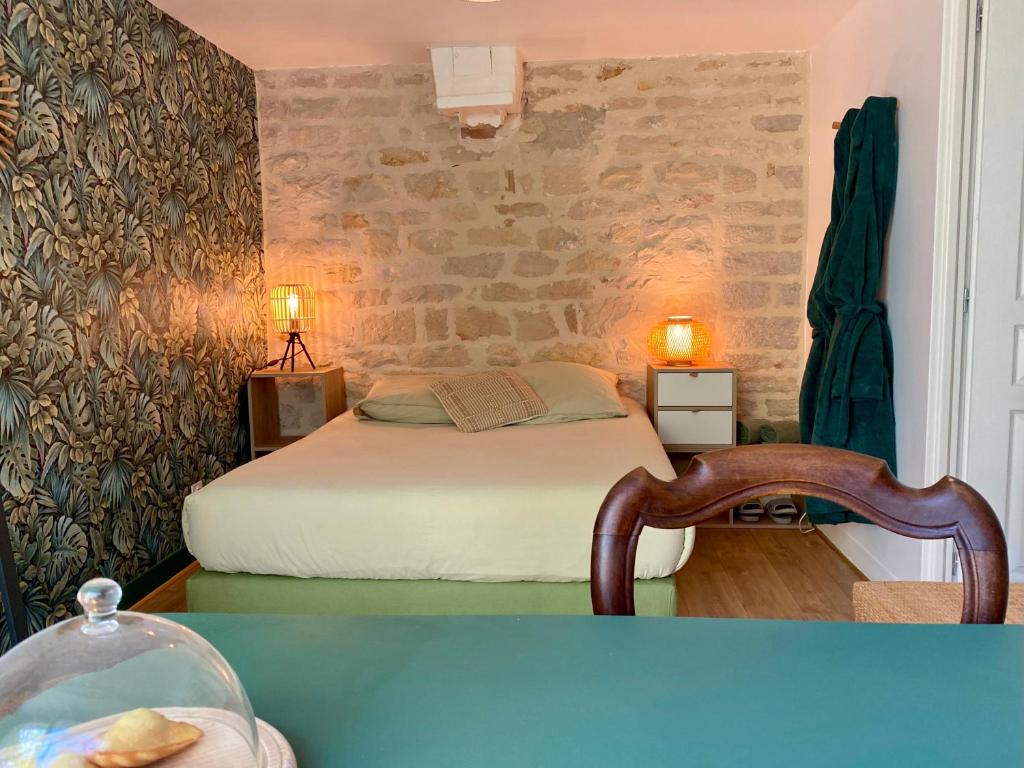 a bedroom with a bed and a stone wall at Chambre Cocoon dans une maison avec SPA et jardin en centre ville in Dijon