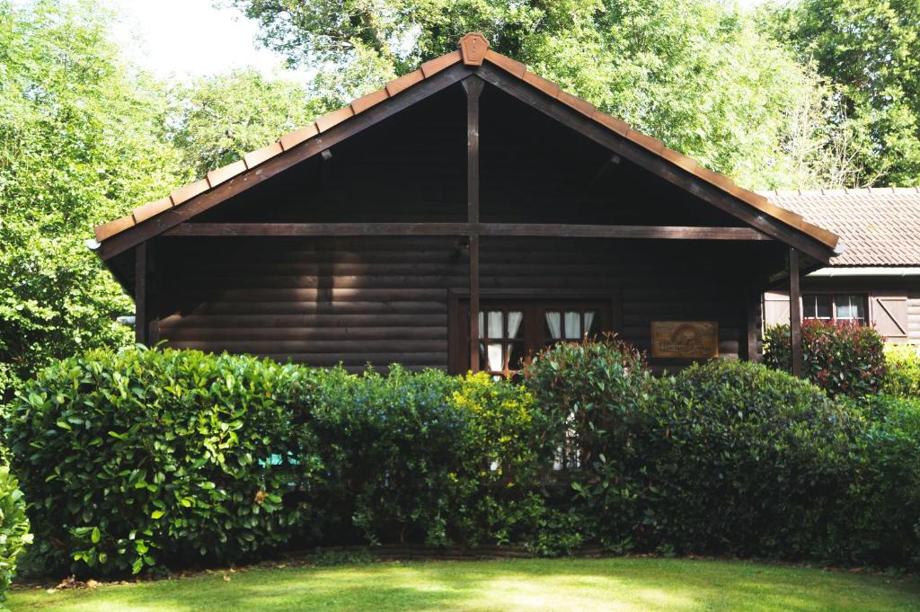 a wooden cabin with a roof over some bushes at La Coterie Lodges in Blaudeix