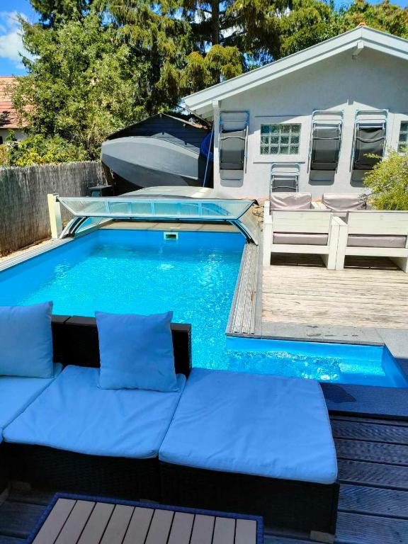 a swimming pool with blue cushions next to a house at Pentz House in Siófok