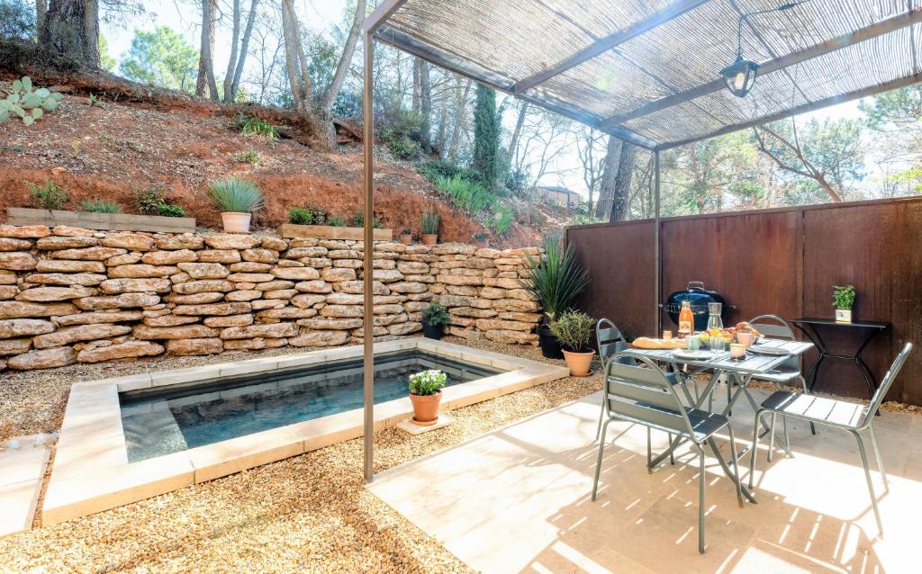 une piscine à l'arrière avec un mur en pierre, une table et des chaises dans l'établissement Mas du Clos , Tilleul, à Roussillon