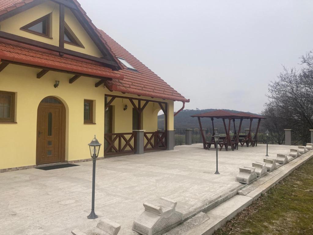 a building with a patio with tables and benches at Bazilika Vendégház in Tarcal