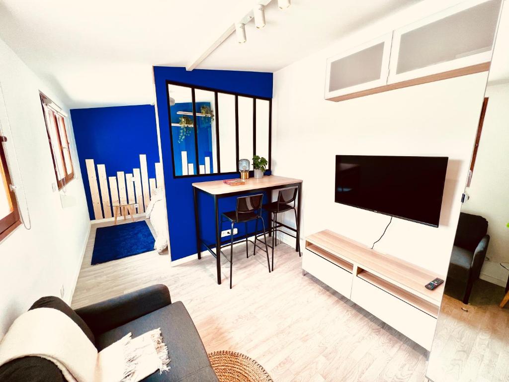 ein Wohnzimmer mit einem Sofa und einem TV in der Unterkunft Les studios de la Villa Jules Verne in Amiens