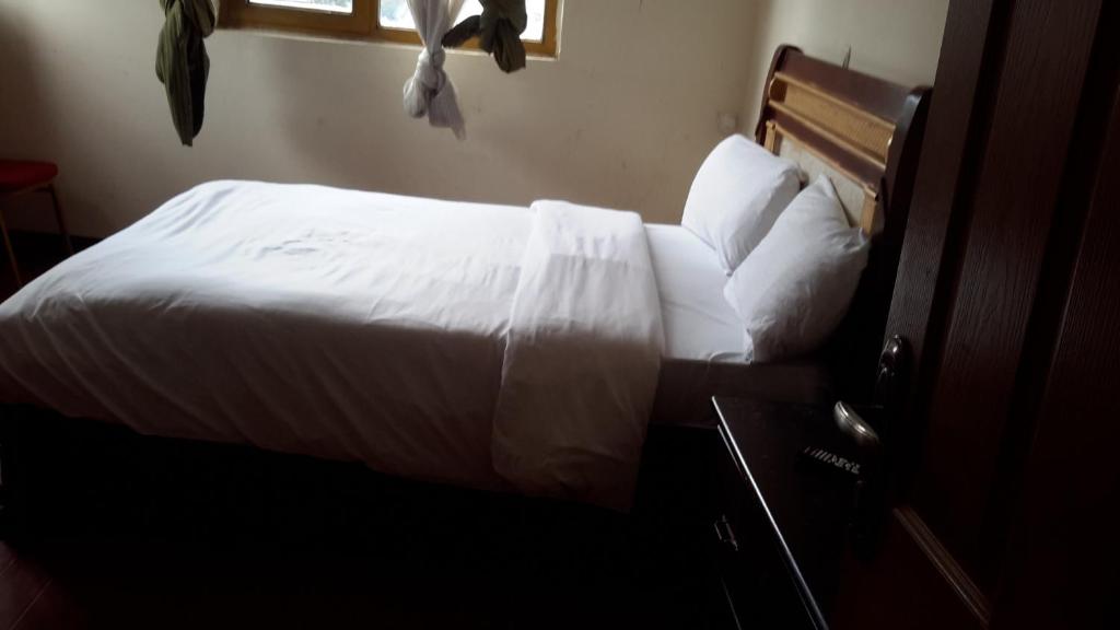 - une chambre avec un lit doté de draps et d'oreillers blancs dans l'établissement GSF Guest House, à Addis-Abeba