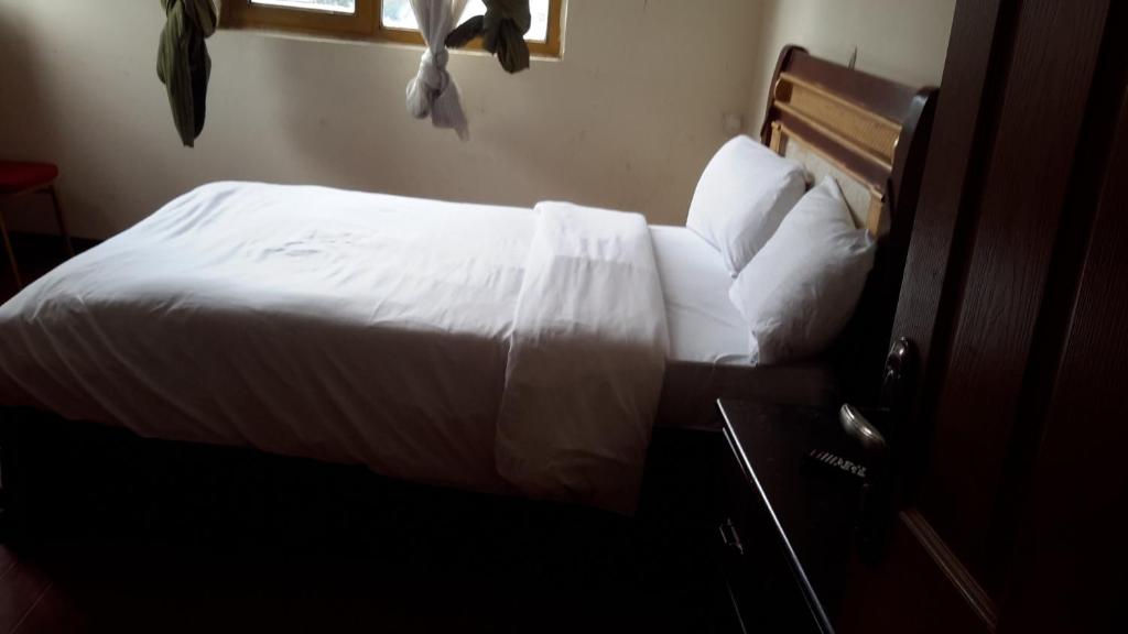 a bedroom with a bed with white sheets and pillows at GSF Guest House in Addis Ababa