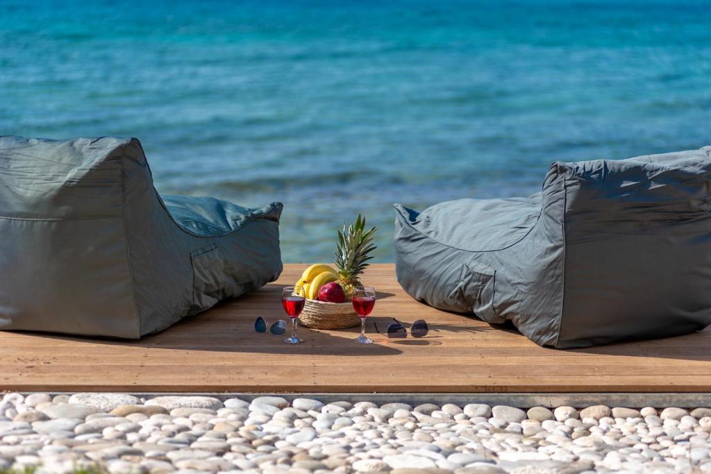 a table with a bowl of fruit on the beach at Junam Private Beachfront Cabins in Agios Nikitas