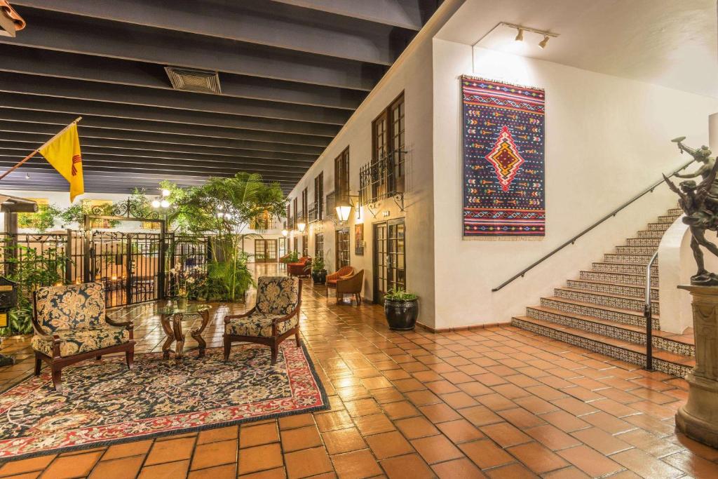 a lobby with two chairs and a staircase with a rug at Ramada by Wyndham Las Cruces Hotel & Conference Center in Las Cruces