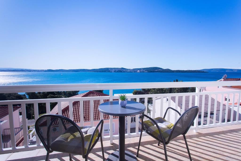 uma mesa e cadeiras num deque com vista para o oceano em Apartments Ana em Trogir