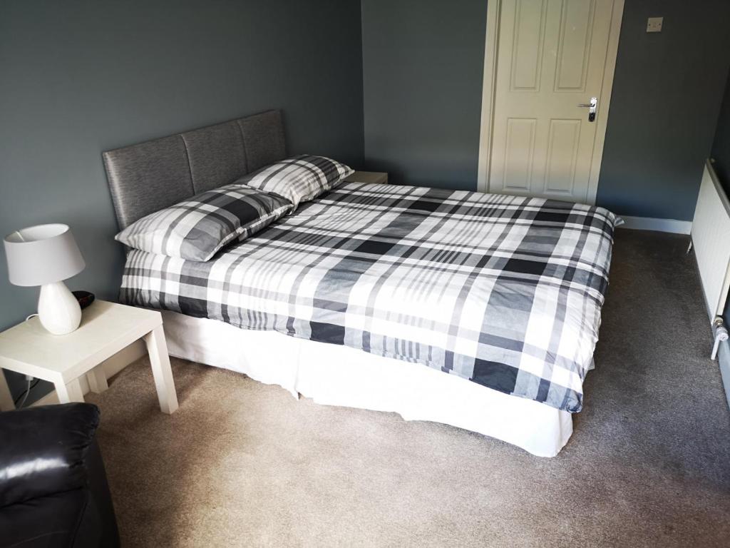 um quarto com uma cama com um cobertor xadrez preto e branco em Copper Coast Hideaway em Tramore