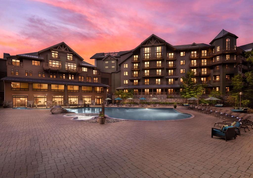 un resort con piscina di fronte a un edificio di The Lodge at Spruce Peak, a Destination by Hyatt Residence a Stowe