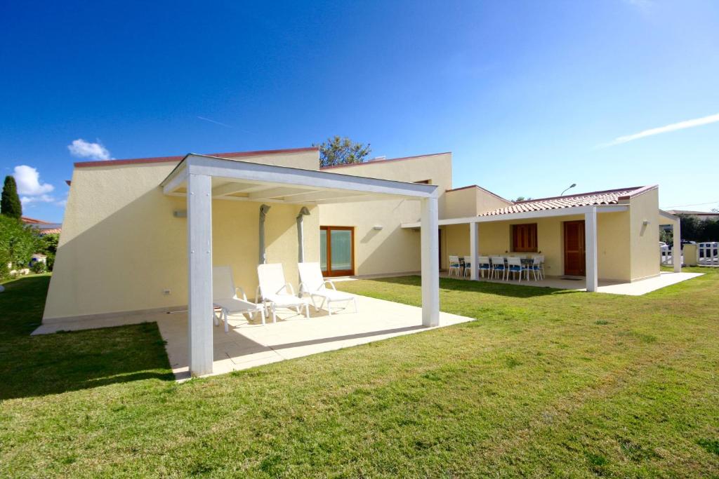 una casa con un ampio cortile con sedie bianche di Villa Franca by Wonderful Italy a San Teodoro