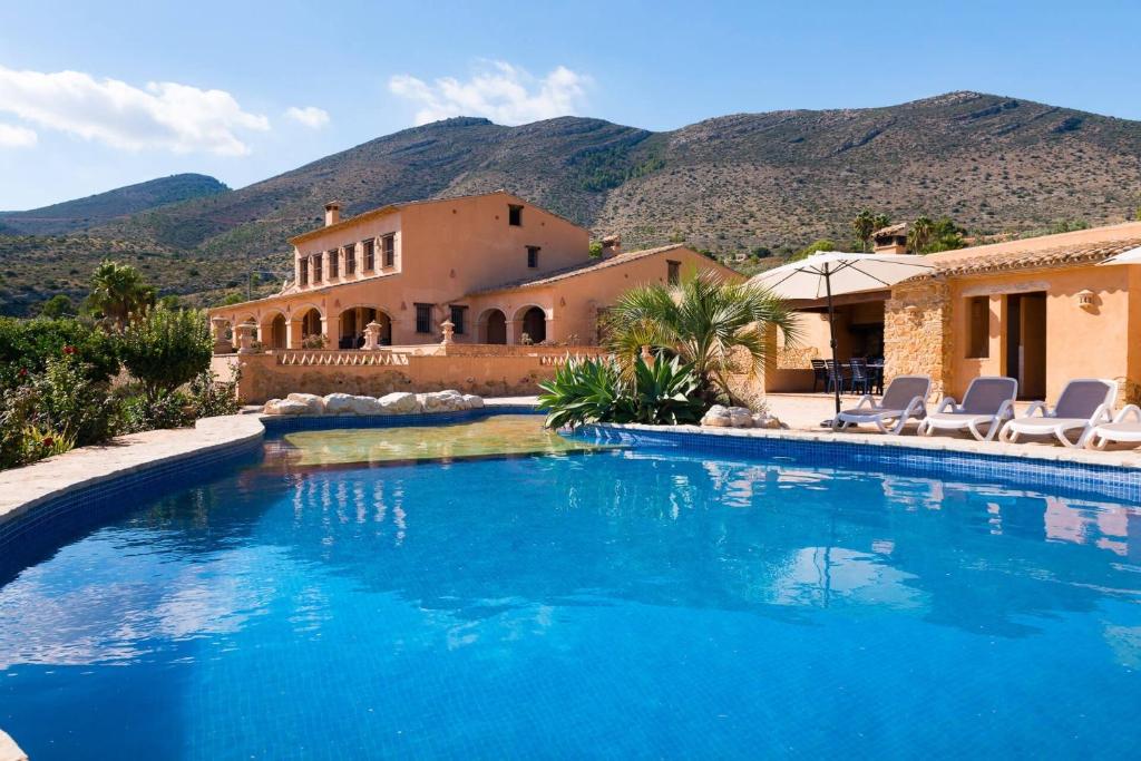 a swimming pool in front of a house with mountains at Villa Paraiso - PlusHolidays in Benissa